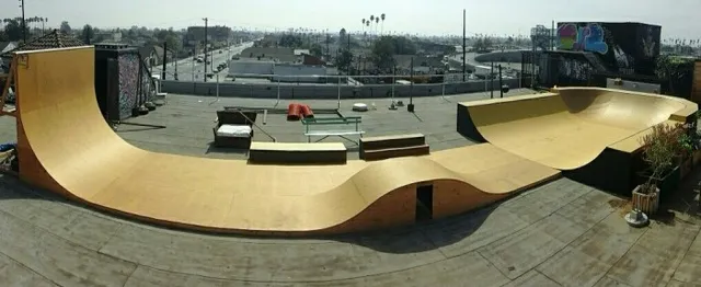 View of rooftop with huge flow park with giant deckless wallride wall, long flat, pump bump, grind box, two step grind box, and long miniramp with extension bowl