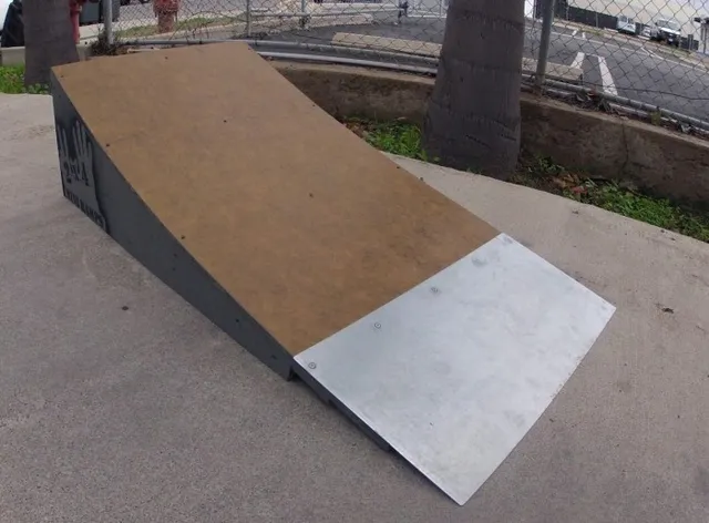 Two foot high launch ramp by fence  near palm tree on concrete, front view