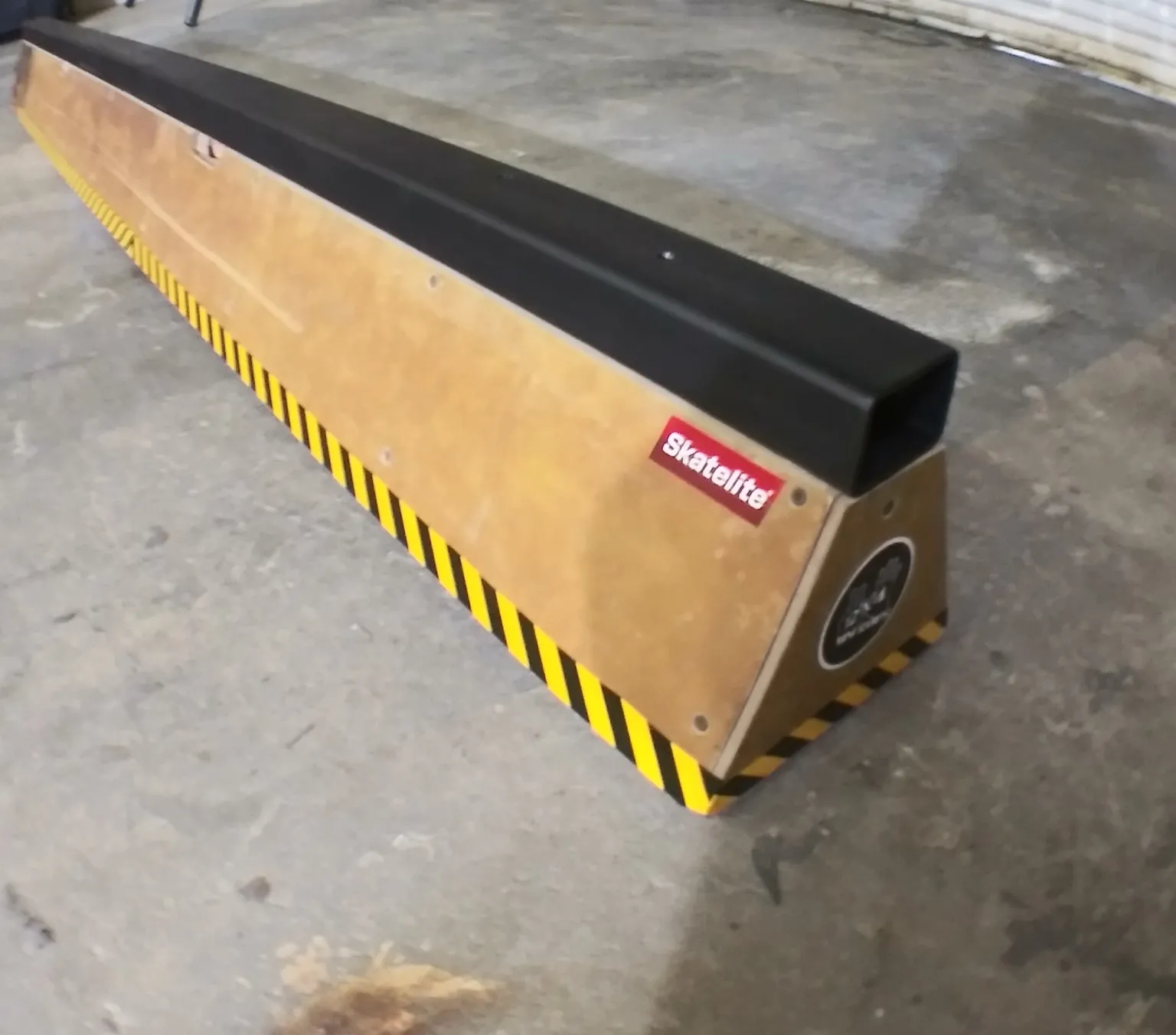 Eight foot long slappy flat bar sitting on concrete, side view